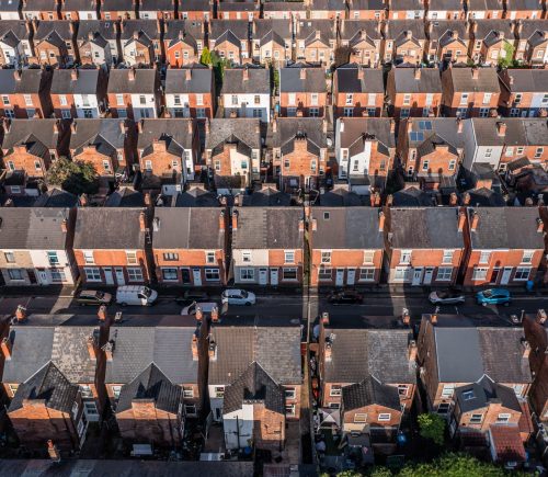 An aerial view above the drab rooftops of run down back to back terraced houses on a large residential estate in the North of England
