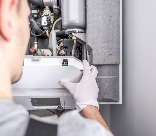 Close Up Of Caucasian Service Worker Fixing Central Heating Furnace System.